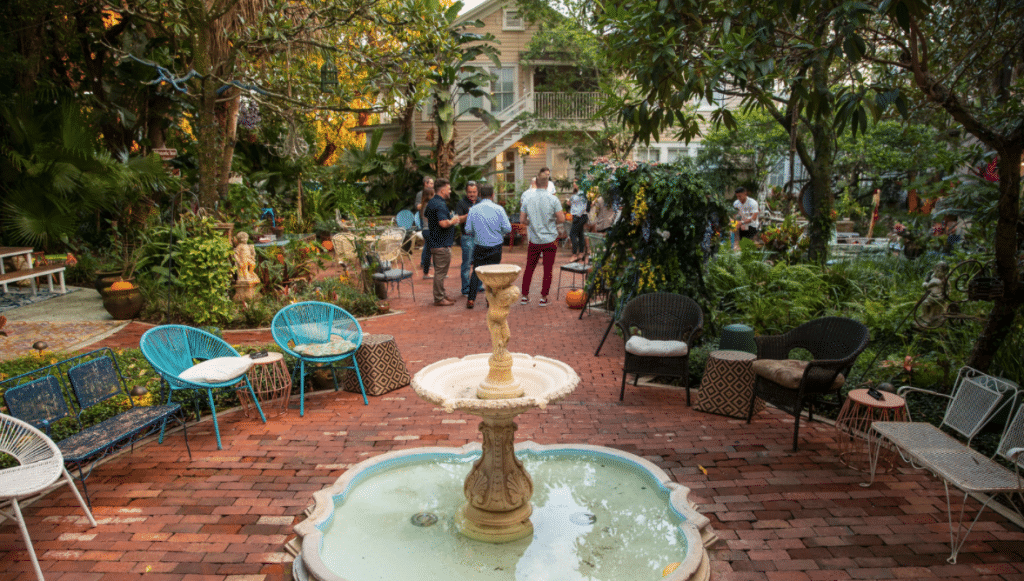 wedding venue brick patio with round fountain, multi color chairs, and guests mingling